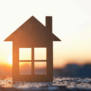 The image is of a cutout wooden house with the sunset behind it. Housing options for people in Guildford